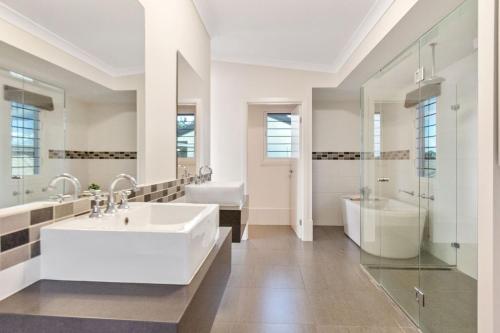 y baño con 2 lavabos, bañera y ducha. en Remarkable Six Bedroom Waterfront Home! Perfect for the extended family en Mooloolaba