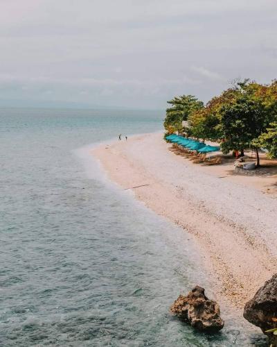 a beach with a group of people in the water at Bluewater Sumilon Island Resort in Sumilon Island
