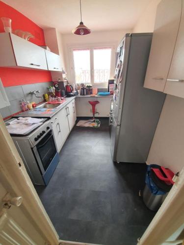 a small kitchen with white cabinets and a refrigerator at Appartement cosy en plein centre in Guidel