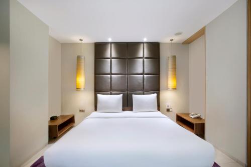 a bedroom with a large white bed and two lights at Holiday Inn Bandung Pasteur by IHG in Bandung