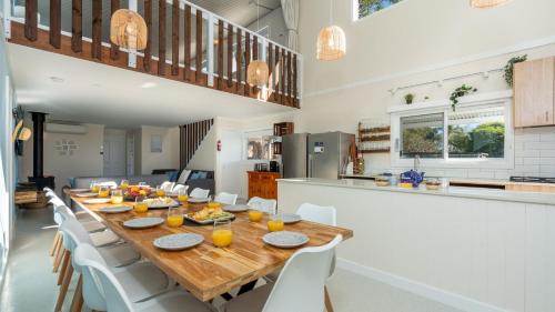 a dining room with a long wooden table and white chairs at The Loft in Culburra Beach