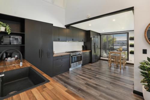 a kitchen with black cabinets and a sink and a table at MOOLOOLABA CANAL HOME - Modern 4Bedroom with Spa, Sauna and Private Pontoon - NEW proprietor 2024 in Mooloolaba