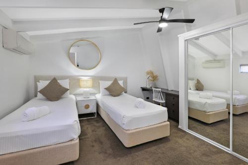 um quarto com 2 camas e um espelho em MOOLOOLABA CANAL HOME - Modern 4Bedroom with Spa, Sauna and Private Pontoon - NEW proprietor 2024 em Mooloolaba