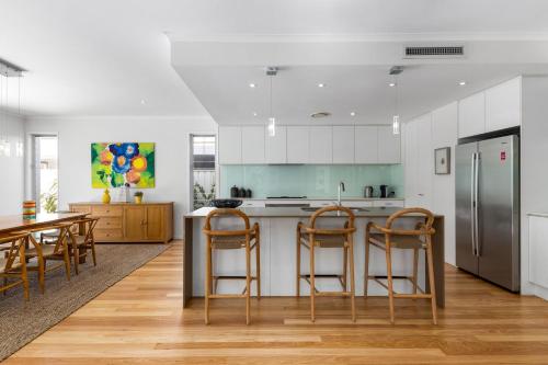 a kitchen with white cabinets and a stainless steel refrigerator at Seaside Beach House in Marcoola