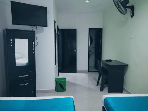 Habitación con 1 dormitorio con escritorio y TV. en HOTEL VILLAMAYOR CABECERA, en Bucaramanga