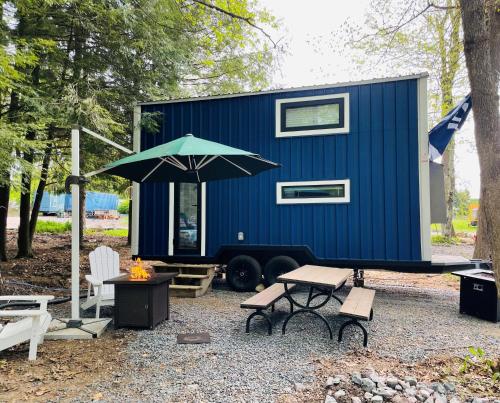 a blue tiny house with a picnic table and an umbrella at Camptel Poconos in Albrightsville