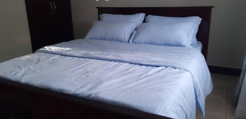 1 cama grande con sábanas y almohadas blancas en Candle Wood Homes, en Lira