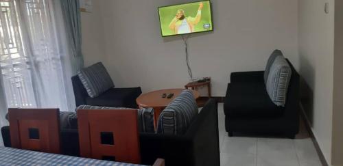a living room with two chairs and a tv at Candle Wood Homes in Lira