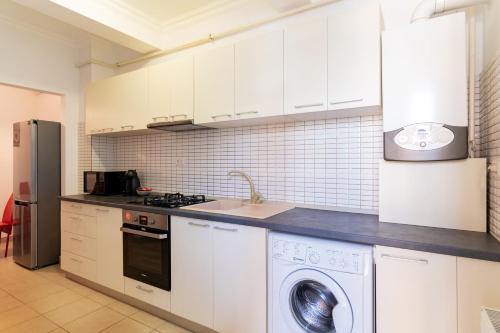 ママイアにあるLuca Solid Residenceの白いキャビネットと洗濯機付きのキッチン