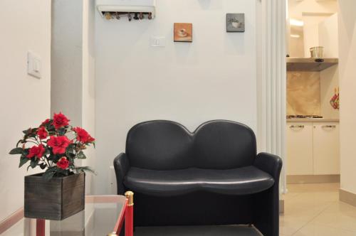 a black chair in a room with a vase of flowers at COZY APARTMENT NEAR RIALTO BRIDGE/ ST.MARK SQUARE in Venice