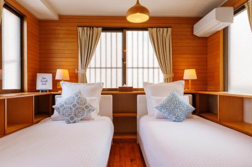 two beds in a room with wooden walls and windows at Naha Gajumaru Apartment Hotel 401 in Naha