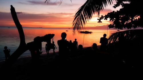 a group of people standing on the beach at sunset at SunnySide bed & bar in Siquijor