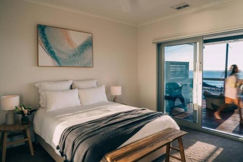 Un dormitorio con una cama y vista al mar. en ōSHEN - Sleeps12 Gym Kayak MountnBike BeachFrnt, en Aldinga Beach