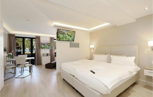 a white bedroom with a large white bed and a desk at Baltic in Binz