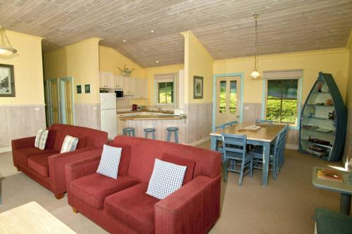 a living room with two red couches and a kitchen at Bennetts Beach House in Apollo Bay