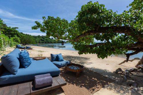 a blue couch and chairs on a beach at Clay Beach Samui - Beachfront Villas in Amphoe Koh Samui