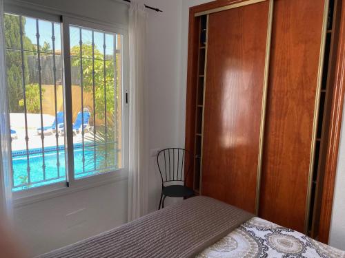 a bedroom with a bed and a window with a pool at Villa Maravilla in Murcia