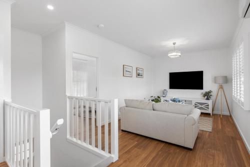 a white living room with a couch and a tv at Foxmount Estate Magnus 2 bedroom in Mount Gambier