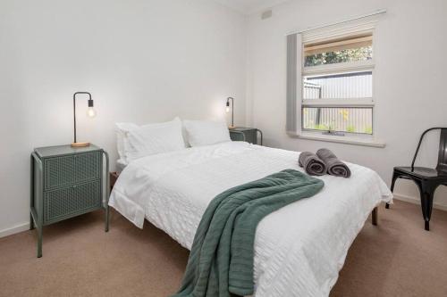 a white bedroom with a bed and a window at Stay Here On Pier- 2 Bdrm Sleeps 4 Beach Wifi in Glenelg