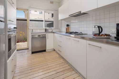 a kitchen with white appliances and a wooden floor at Stay Here On Pier- 2 Bdrm Sleeps 4 Beach Wifi in Glenelg