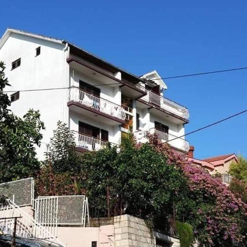a white apartment building with balconies and trees at Privatan smeštaj Igalo in Igalo