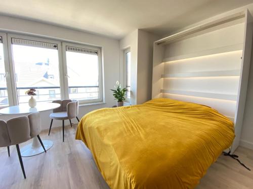 a bedroom with a yellow bed and a table at Happy stay by Anaïs - 20m to beach in De Panne
