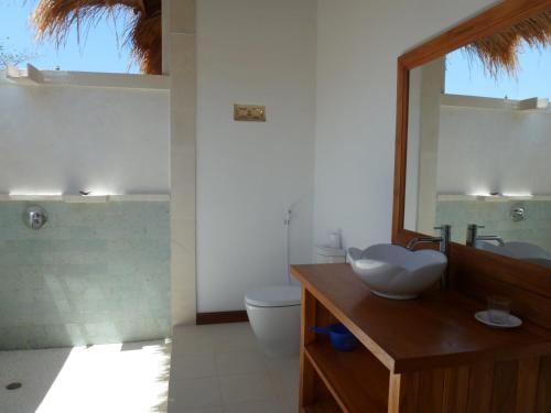 bagno con lavandino, servizi igienici e specchio di Sunia Loka Bungalows & Dive Center a Pemuteran