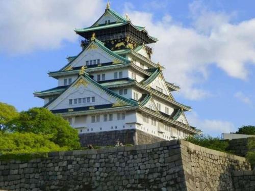 a large japanese castle with a wall in front of it at Ark Hotel Osaka Shinsaibashi -ROUTE INN HOTELS- in Osaka