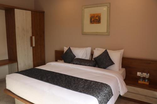 a bedroom with a large white bed with black pillows at Nest Beacon Resort Daman in Daman