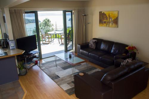 a living room with a leather couch and a table at Allegra House in Paihia
