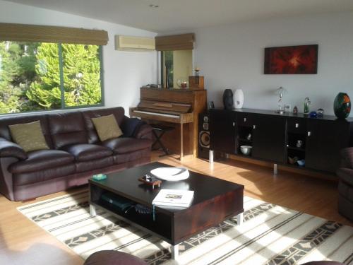 a living room with a couch and a piano at Allegra House in Paihia