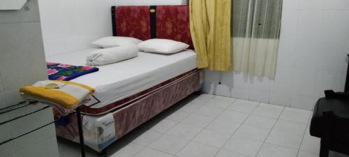 um pequeno quarto com uma cama e uma cortina amarela em EXPRESS O 91176 Hotel Puri Gandaria em Parepare