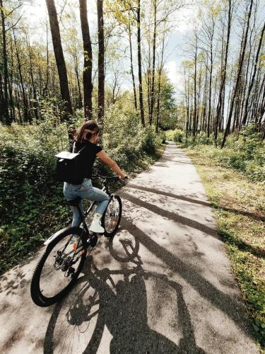 a woman riding a bike down a dirt road at Forest Studio in Druskininkai