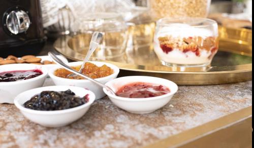 a counter topped with bowls of desserts and a plate of food at The Negev Hotel By Domus in Beer Sheva