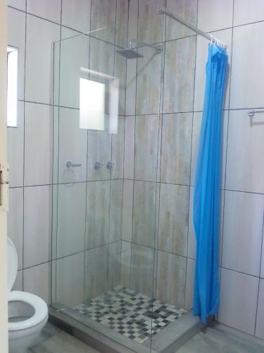 a shower with a blue shower curtain in a bathroom at Amariah Lodge in Kasane