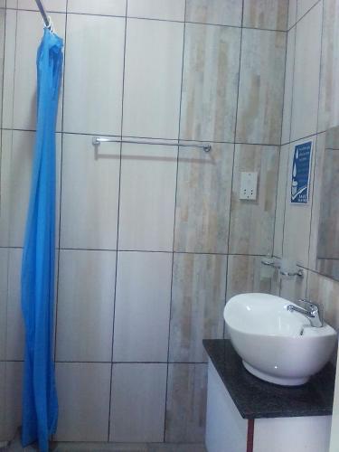 a bathroom with a white sink and a shower at Amariah Lodge in Kasane