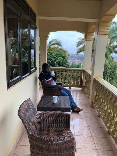 a woman sitting on a porch on a balcony at Prax suits in Kampala