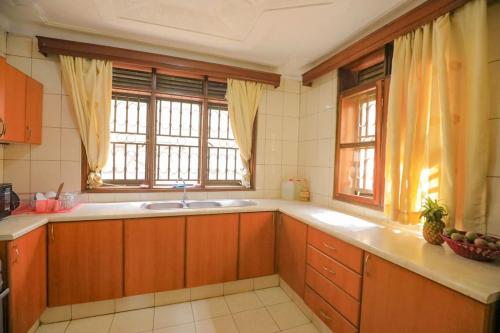 cocina con armarios de madera, fregadero y ventana en Prax suits, en Kampala