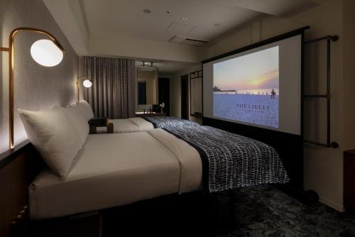 ein Hotelzimmer mit einem großen Bett und einer Leinwand in der Unterkunft The Lively Osaka Honmachi in Osaka
