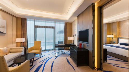 a hotel room with a bed and a living room at Wyndham Chongqing Yuelai in Chongqing