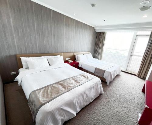 a hotel room with two beds and a large window at APVC Lukang Resort in Lugang