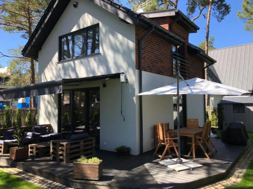 a white house with a table and an umbrella at Villa Ohana in Pobierowo 300 m from the beach in Pobierowo