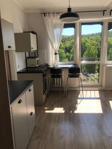 een keuken met een tafel en stoelen en een groot raam bij Apartament la mar in Sopot