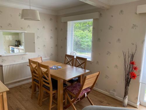 a dining room with a wooden table and chairs at Lovely Bournemouth cottage with beautiful large garden, 5 min to the beach by car in Bournemouth