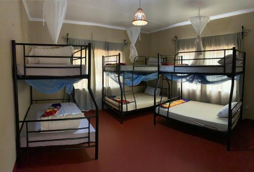 a room with three bunk beds in a room at Pazuri Hostel in Moshi