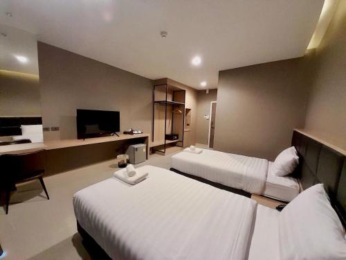 a hotel room with two beds and a flat screen tv at S.R.SUNSHINE HOTEL in Ban Sok Dua