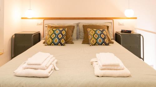 1 dormitorio con 1 cama con toallas en Welcomely - Civico 65-40, en Nuoro