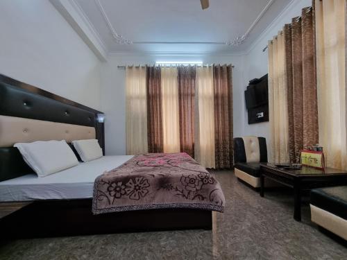 a bedroom with a bed and a table and a couch at Hotel Vivek Nomadic in Dalhousie