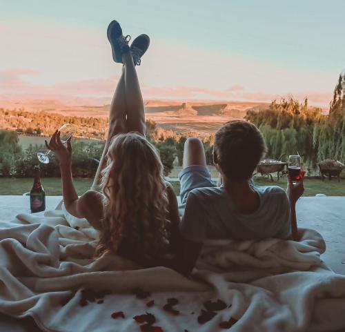 a group of three people laying on a bed with drinks at The Fat Mulberry Guest Farm in Fouriesburg