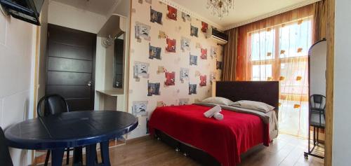 a bedroom with a bed with a red blanket and a table at Dzveli Batumi in Batumi
